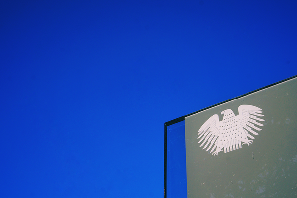Der Bundesadler von Deutschland auf einer Metall-Stele. Im Hintergrund ein wolkenloser, blauer Himmel.
