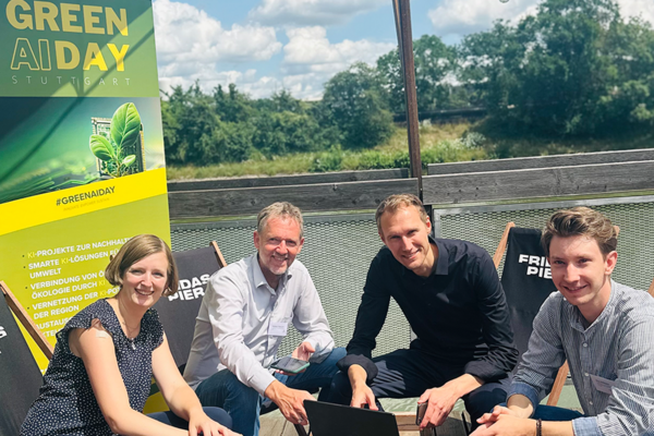 Vier Personen schauen in die Kamera. Im Hintergrund steht ein Roll-up zur Veranstaltung Green AI Day Stuttgart. Bildrechte: Landeshauptstadt Stuttgart.