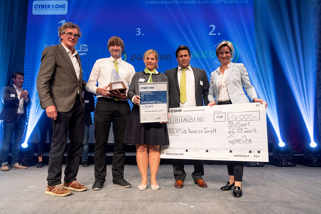 Ein Gewinnerteam des Businessplanwettbewerbs CyberOne Hightech Award posiert mit einem Gewinnscheck auf der Bühne.