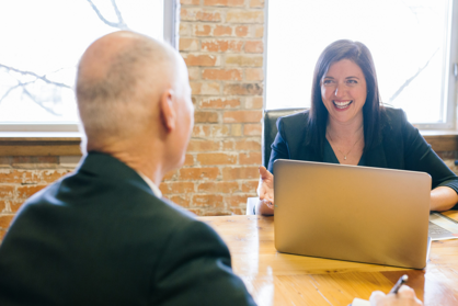 Eine Frau und ein Mann sitzen sich gegenüber und unterhalten sich über eine Unternehmensnachfolge.