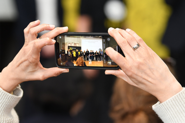 Eine Frau fotografiert mit ihrem Smartphone das Start-up BW Team auf der Bühne der 11. Start-up BW Arbeitstagung in Bad Boll.