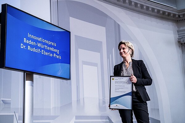 Ein Foto von der Preisverleihung des Innovationspreises des Landes Baden-Württember 2020. Wirtschaftsministerin Dr. Nicole Hoffmeister-Kraut hält eine Urkunde in den Händen. Credits: Tom Maurer Photography