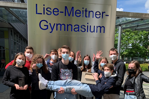 Ein Jubelfoto der Schülerfirma Kill'D'Bazill aus Baden-Württemberg. Das Team freut sich jubelnd und mit Pokal über den zweiten Platz beim JUNIOR Bundeswettbewerb. Die Schülerfirma kommt vom Liste-Meitner-Gymnasium, Königsbach-Stein.