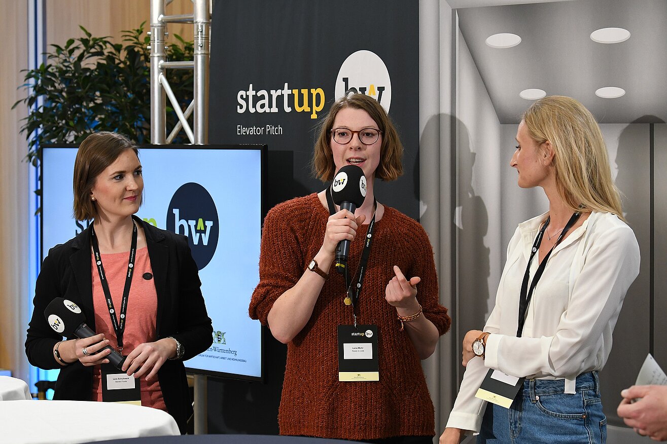 Drei Frauen pitchen ihre Geschäftsidee auf der Bühne beim Start-up BW Elevator Pitch.