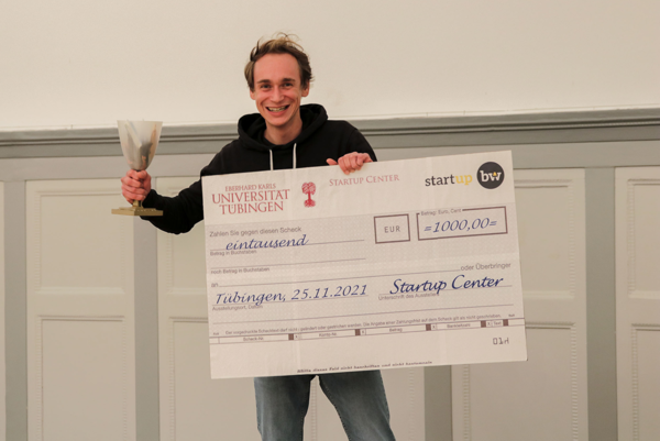 Gründer mit Gewinnerscheck und Pokal.