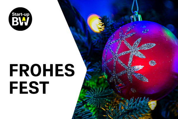 Eine Christbaumkugel an einem beleuchteten und geschmückten Nadelbaum. Logo Start-up BW und Text "FROHES FEST".