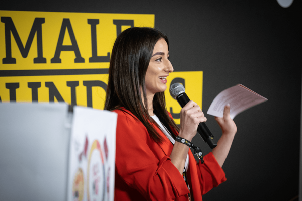 Eine Gründerin steht auf der Pitch-Bühne im Rahmen des Female Founders Cup 2022 und präsentiert ihre Geschäftsidee. Im Hintergrund ist ein Banner mit dem Aufdruck FEMALE FOUNDERS.