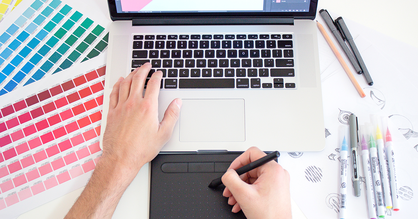 Eine Person arbeitet an einem Laptop mit verschiedenen Farbpaletten an einem neuen Design.