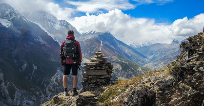 Ein Wanderer steht auf einem Berggipfel.
