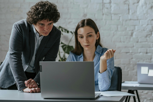Ein Mann und eine Frau schauen gemeinsam auf den Bildschirm eines Laptops.