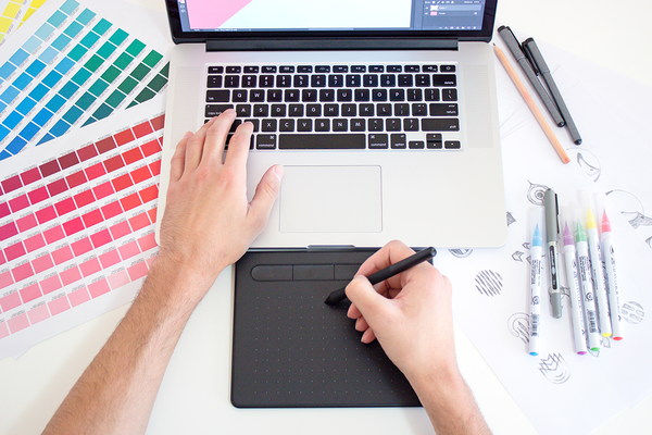 Eine Person arbeitet an einem Laptop mit verschiedenen Farbpaletten an einem neuen Design.