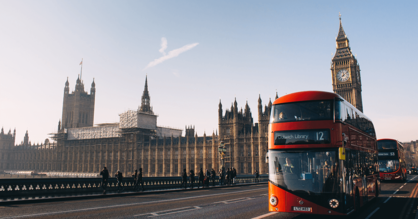 Fotoaufnahme von einem roten Doppeldeckerbus vor dem Palace of Westminster und dem Elizabeth Tower im Hintergrund.