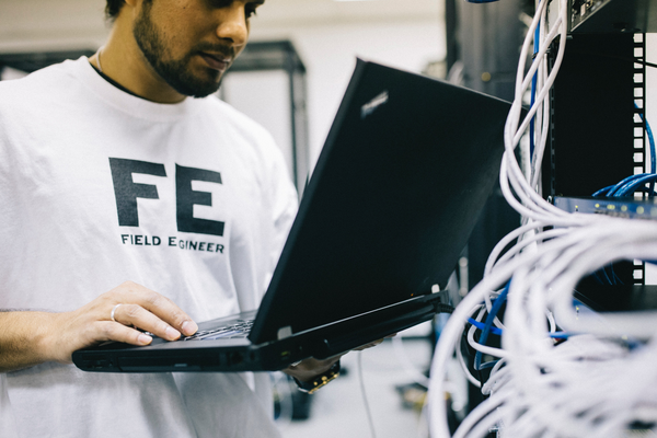 Techniker in einem Serverraum mit Laptop.