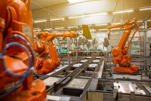 Es sind drei Roboter einer Werkzeugmaschine in einer Fabrik abgebildet.